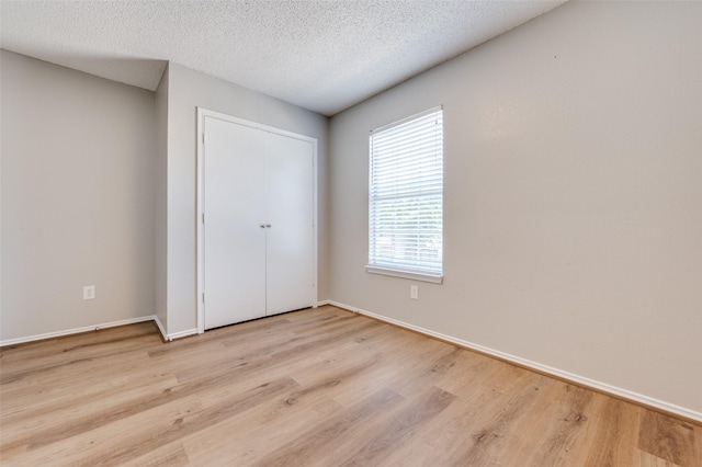 2521 Markland St, Irving, TX 75060 - unfurnished bedroom featuring wood finished floors, baseboards, a textured ceiling, and a closet