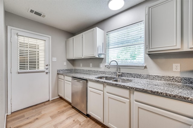 2521 Markland St, Irving, TX 75060 - kitchen with dishwasher, a sink, light wood finished floors, light stone counters, and a textured ceiling