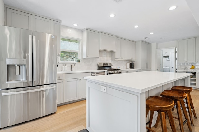 328 High Brook Dr, Richardson, TX 75080 - kitchen with appliances with stainless steel finishes, a breakfast bar area, tasteful backsplash, a sink, and light wood finished floors