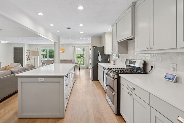 328 High Brook Dr, Richardson, TX 75080 - kitchen featuring appliances with stainless steel finishes, light wood-style floors, a kitchen island, open floor plan, and light countertops