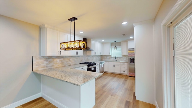 2210 Mcclure St, Irving, TX 75062 - kitchen with black range with gas cooktop, wall chimney range hood, stainless steel dishwasher, a sink, and white cabinetry