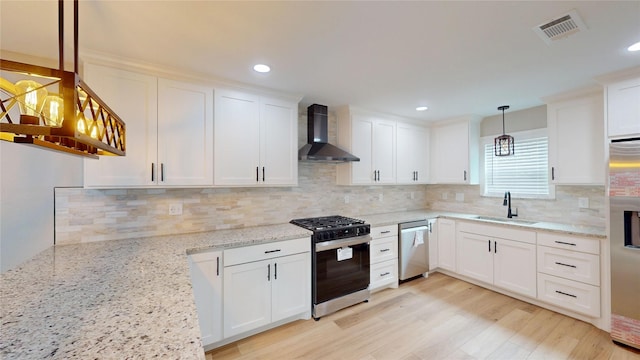 2210 Mcclure St, Irving, TX 75062 - kitchen featuring appliances with stainless steel finishes, wall chimney range hood, a sink, white cabinets, and recessed lighting
