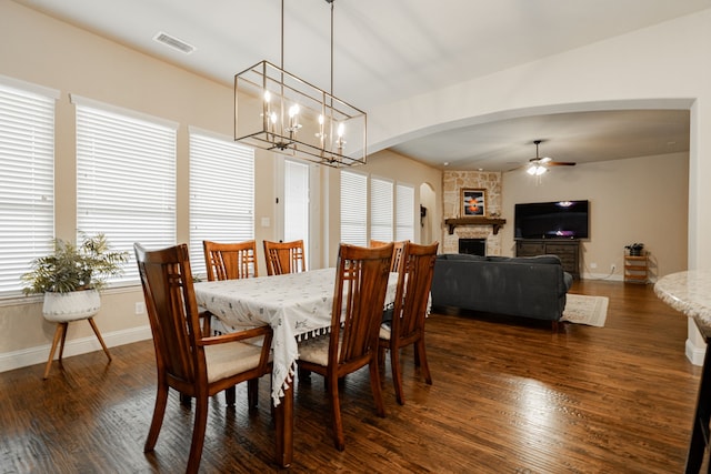 817 Calm Crest Dr, Rockwall, TX 75087 - dining area featuring a ceiling fan, dark wood-style flooring, a fireplace, a chandelier, and arched walkways