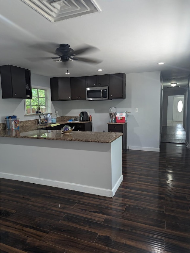 3108 Bideker Ave, Fort Worth, TX 76105 - kitchen with stainless steel microwave, dark stone countertops, a peninsula, dark cabinets, and recessed lighting