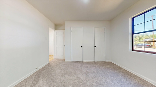3809 Grover Ave, Fort Worth, TX 76106 - unfurnished bedroom featuring light carpet, baseboards, and two closets