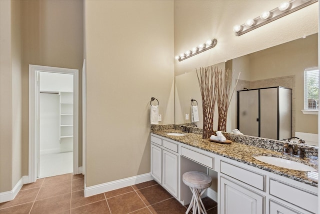 13929 Castlegate Dr, Frisco, TX 75035 - bathroom featuring a shower stall, double vanity, tile patterned flooring, a walk in closet, and baseboards