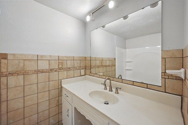 2913 Portales Dr, Fort Worth, TX 76116 - bathroom with tile walls, vanity, a textured ceiling, wainscoting, and a shower