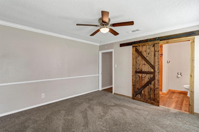 616 Bellevue Dr, Cleburne, TX 76033 - unfurnished bedroom with a barn door, crown molding, carpet floors, baseboards, and a textured ceiling