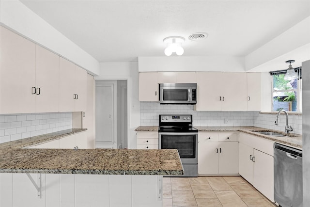 10533 Solta Dr, Dallas, TX 75218 - kitchen featuring appliances with stainless steel finishes, a sink, a peninsula, backsplash, and light stone countertops