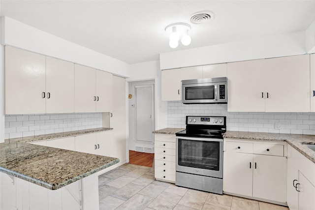10533 Solta Dr, Dallas, TX 75218 - kitchen with stainless steel appliances, tasteful backsplash, a peninsula, and light stone countertops