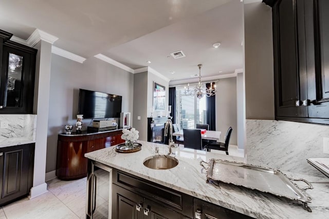 2525 N Pearl St Unit 1704, Dallas, TX 75201 - kitchen featuring a sink, dark cabinets, a chandelier, ornamental molding, and light stone countertops