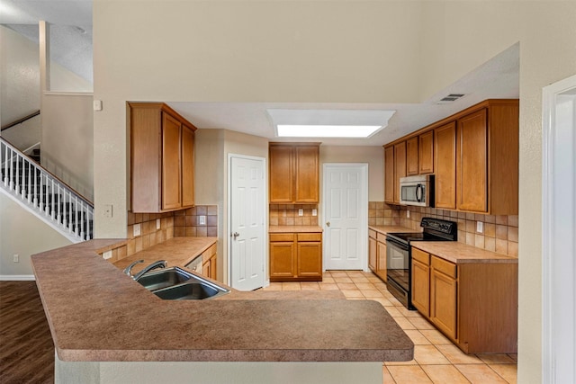 4953 Sunset Ridge Dr, Fort Worth, TX 76123 - kitchen featuring black range with electric cooktop, stainless steel microwave, a sink, a peninsula, and backsplash