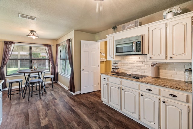 3701 Nocona Dr, Granbury, TX 76049 - kitchen with stainless steel microwave, black electric cooktop, a textured ceiling, decorative backsplash, and dark wood-style flooring