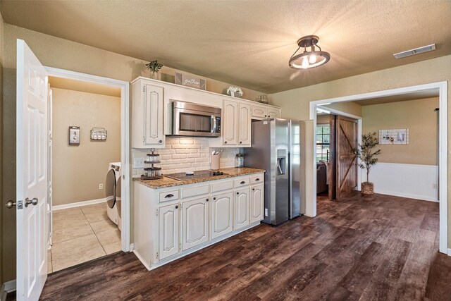 3701 Nocona Dr, Granbury, TX 76049 - kitchen featuring appliances with stainless steel finishes, separate washer and dryer, dark wood-style flooring, light stone counters, and decorative backsplash