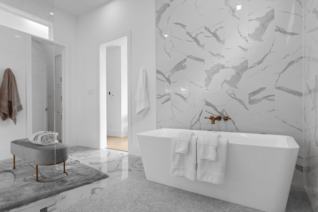 317 Rusk St, Roanoke, TX 76262 - bathroom featuring stone wall, a freestanding bath, and marble tiled flooring