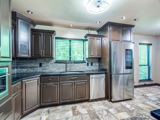 18636 Crownover Ct, Dallas, TX 75252 - kitchen featuring appliances with stainless steel finishes, a sink, backsplash, dark stone countertops, and stone tile floors