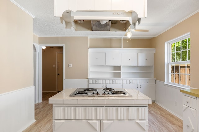2111 Chippendale Dr, Mckinney, TX 75071 - kitchen with tile counters, white electric stovetop, light wood-type flooring, crown molding, and white cabinets