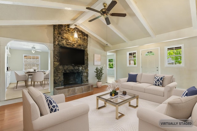 2111 Chippendale Dr, Mckinney, TX 75071 - living room featuring ceiling fan, wood finished floors, a stone fireplace, and arched walkways