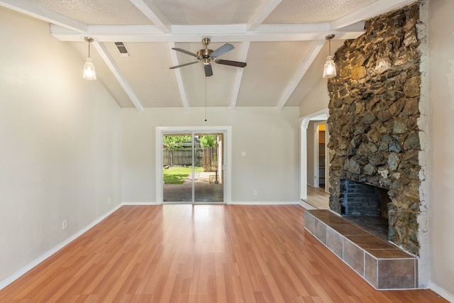 2111 Chippendale Dr, Mckinney, TX 75071 - unfurnished living room featuring ceiling fan, light wood-style flooring, a stone fireplace, baseboards, and arched walkways