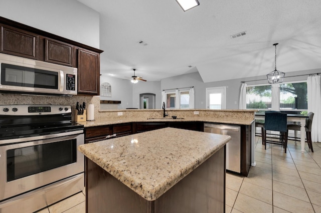 3214 Eagle Ln, Midlothian, TX 76065 - kitchen featuring stainless steel appliances, a sink, a kitchen island, dark brown cabinetry, and a peninsula