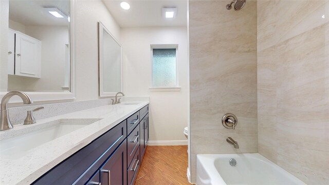 2350 Ravenwood Dr, Grand Prairie, TX 75050 - full bathroom featuring double vanity, toilet, shower / washtub combination, wood finished floors, and baseboards