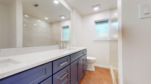 2350 Ravenwood Dr, Grand Prairie, TX 75050 - bathroom with toilet, double vanity, healthy amount of natural light, wood finished floors, and recessed lighting