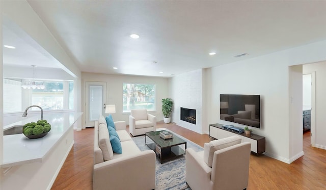 2350 Ravenwood Dr, Grand Prairie, TX 75050 - living room with light wood-type flooring, a large fireplace, recessed lighting, baseboards, and a chandelier