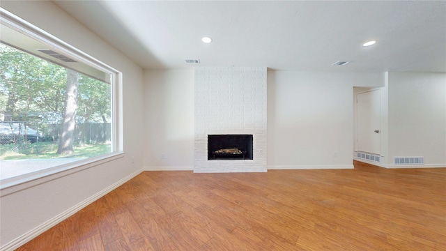 2350 Ravenwood Dr, Grand Prairie, TX 75050 - unfurnished living room with light wood-type flooring, a brick fireplace, baseboards, and recessed lighting