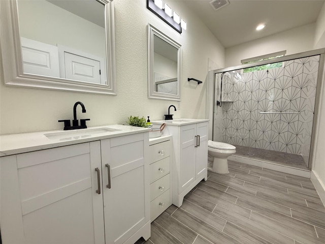 201 E 10th St, Kaufman, TX 75142 - bathroom featuring toilet, a stall shower, vanity, wood finish floors, and recessed lighting