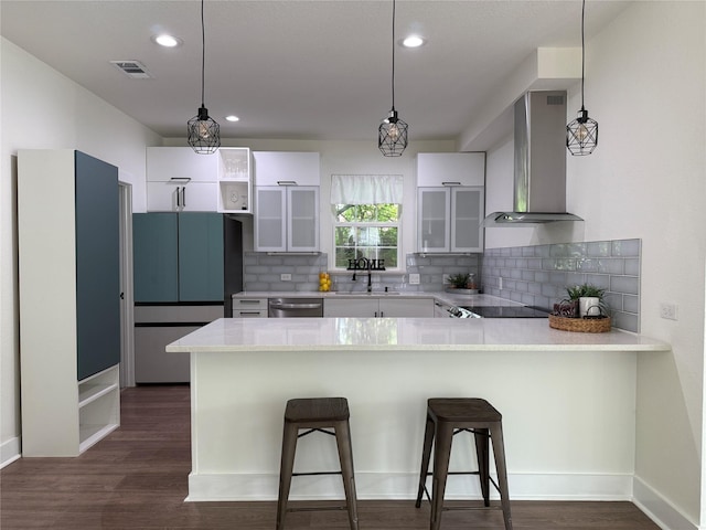 201 E 10th St, Kaufman, TX 75142 - kitchen featuring wall chimney exhaust hood, a peninsula, refrigerator, tasteful backsplash, and white cabinetry