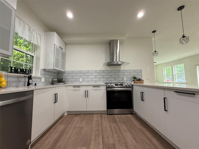 201 E 10th St, Kaufman, TX 75142 - kitchen with appliances with stainless steel finishes, wall chimney exhaust hood, wood finished floors, light countertops, and recessed lighting