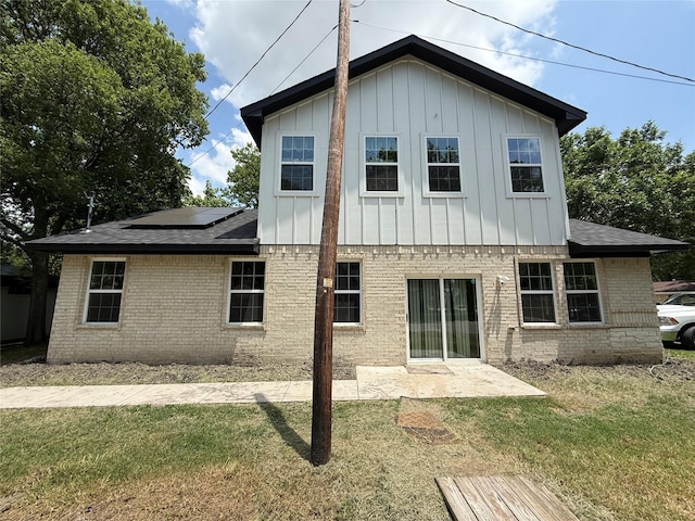 201 E 10th St, Kaufman, TX 75142 - back of property with board and batten siding, brick siding, roof mounted solar panels, a yard, and a patio area