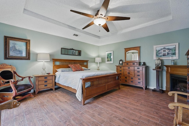2739 Timberleaf Dr, Carrollton, TX 75006 - bedroom featuring a tray ceiling, wood finished floors, a textured ceiling, a fireplace, and baseboards