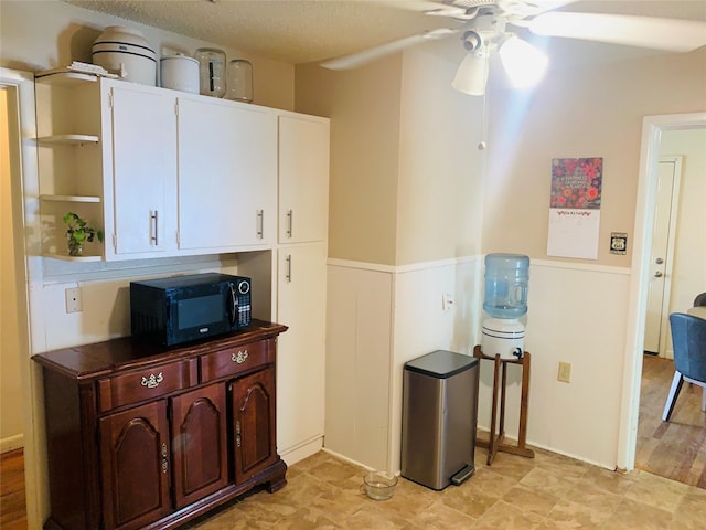 2009 W Way, Garland, TX 75042 - kitchen with black microwave, open shelves, a ceiling fan, a wainscoted wall, and white cabinets