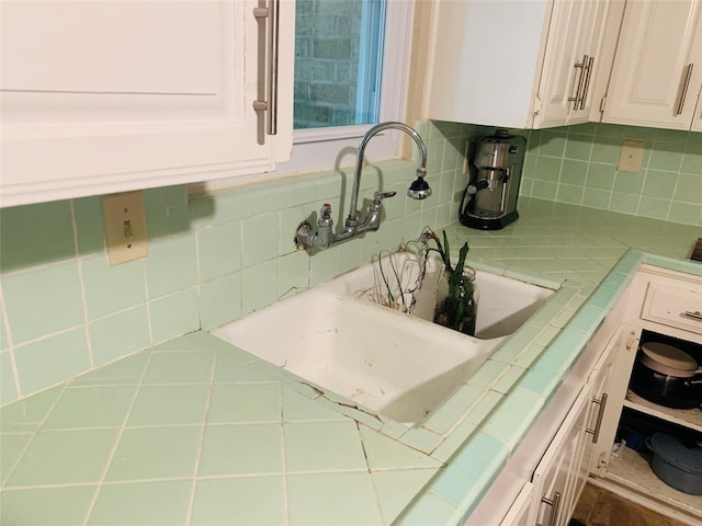 2009 W Way, Garland, TX 75042 - kitchen featuring tile countertops, decorative backsplash, a sink, and white cabinetry