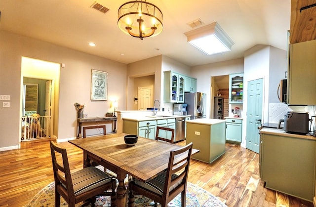 1320 Cedar Branch Dr, Wylie, TX 75098 - kitchen featuring appliances with stainless steel finishes, a center island, light wood-type flooring, light countertops, and glass insert cabinets