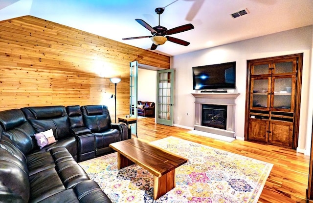 1320 Cedar Branch Dr, Wylie, TX 75098 - living room with a fireplace with raised hearth, a ceiling fan, wood walls, wood finished floors, and baseboards