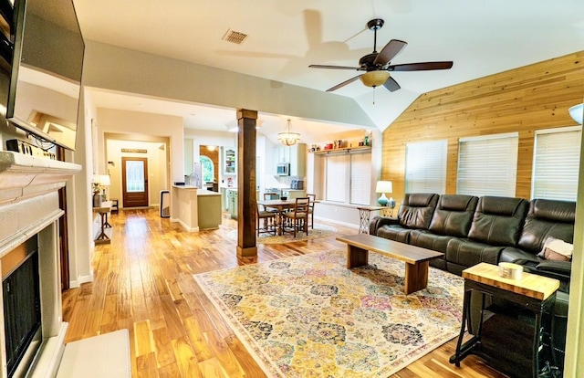 1320 Cedar Branch Dr, Wylie, TX 75098 - living area featuring a fireplace, decorative columns, wooden walls, lofted ceiling, and light wood-style flooring