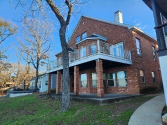 180 Shady Shores Dr, Mabank, TX 75156 - back of property featuring a balcony, brick siding, and a chimney