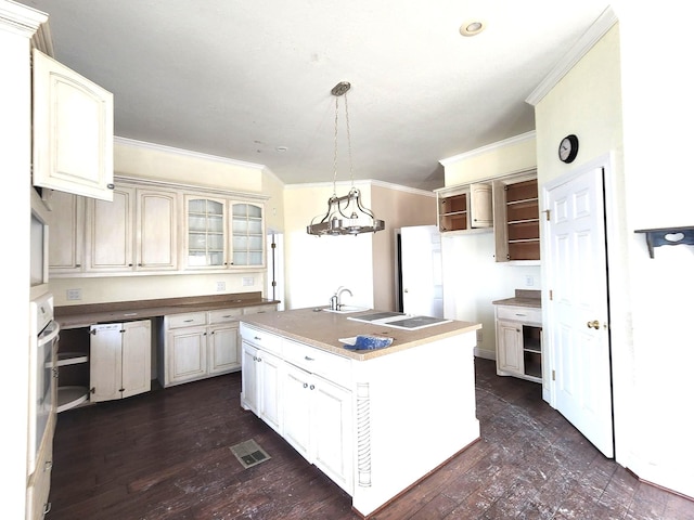180 Shady Shores Dr, Mabank, TX 75156 - kitchen featuring ornamental molding, a kitchen island with sink, glass insert cabinets, hanging light fixtures, and dark wood-style floors
