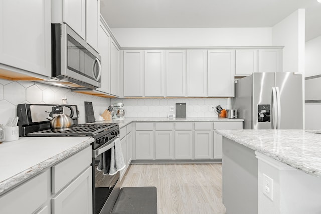 1302 Canyon Creek Rd, Wylie, TX 75098 - kitchen featuring stainless steel appliances, light wood-style flooring, backsplash, and light stone counters