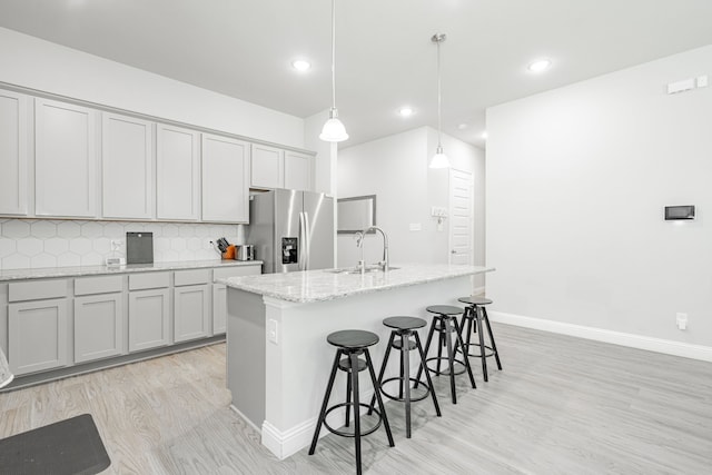 1302 Canyon Creek Rd, Wylie, TX 75098 - kitchen with stainless steel refrigerator with ice dispenser, light wood-style floors, a sink, a kitchen bar, and decorative backsplash
