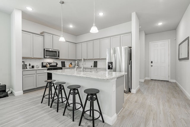 1302 Canyon Creek Rd, Wylie, TX 75098 - kitchen featuring stainless steel appliances, a sink, a kitchen bar, an island with sink, and gray cabinets