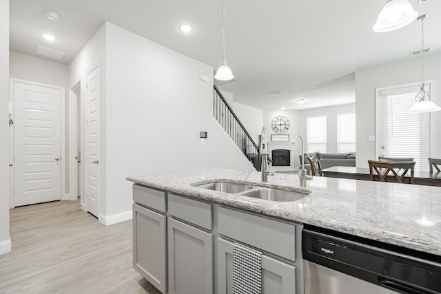 1302 Canyon Creek Rd, Wylie, TX 75098 - kitchen with dishwasher, a sink, baseboards, a glass covered fireplace, and light stone countertops