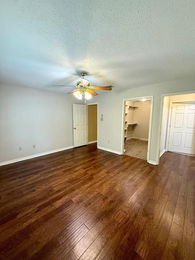 11535 Timber Ridge Dr, Keithville, LA 71047 - unfurnished bedroom featuring dark wood-type flooring, a textured ceiling, baseboards, ceiling fan, and a spacious closet