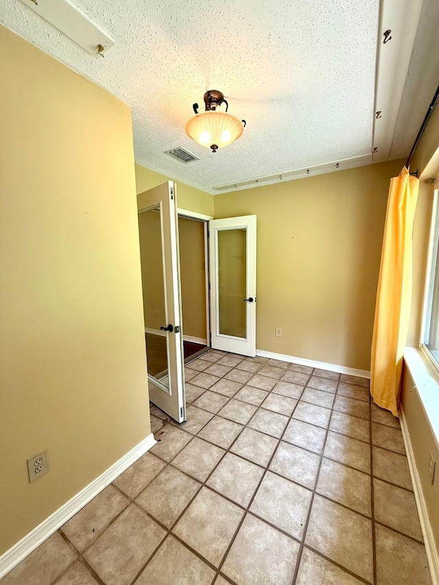 11535 Timber Ridge Dr, Keithville, LA 71047 - unfurnished room with french doors, a textured ceiling, light tile patterned flooring, and baseboards
