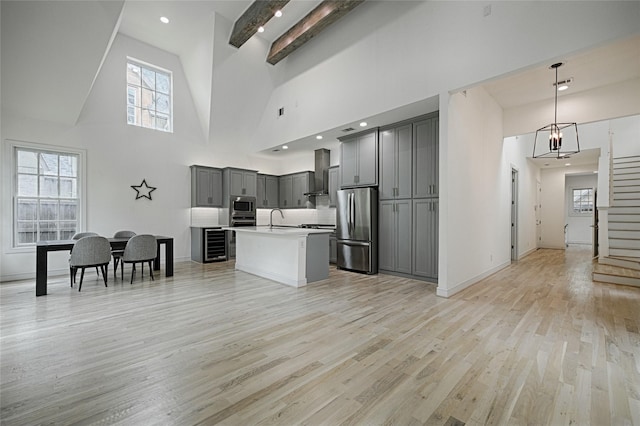 5067 Gaston Ave, Dallas, TX 75214 - kitchen with stainless steel appliances, gray cabinets, a sink, high vaulted ceiling, and wall chimney range hood