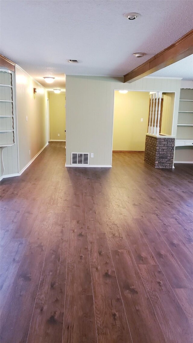 401 S Timberlane, Lone Star, TX 75638 - unfurnished living room with hardwood / wood-style flooring, baseboards, a textured ceiling, built in shelves, and beam ceiling