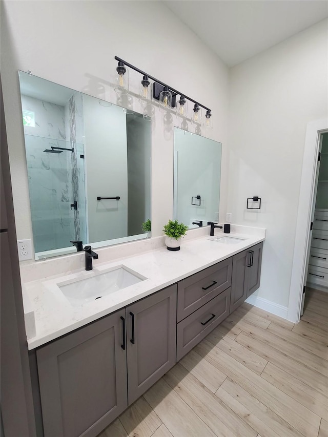1506 Sayle St, Greenville, TX 75401 - full bathroom with double vanity, a marble finish shower, wood finished floors, and baseboards