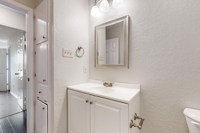 6432 Melinda Ct, Watauga, TX 76148 - bathroom with a textured wall, vanity, toilet, and wood finished floors